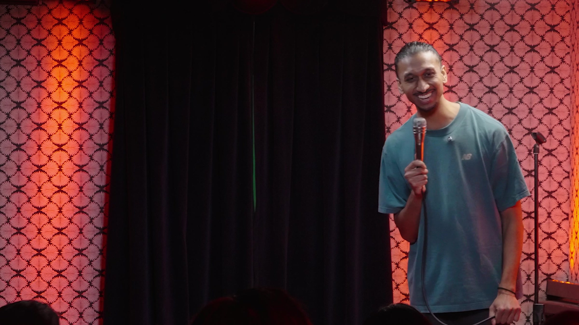 Rah Nimmy laughing and leaning toward the audience during his stand-up special
